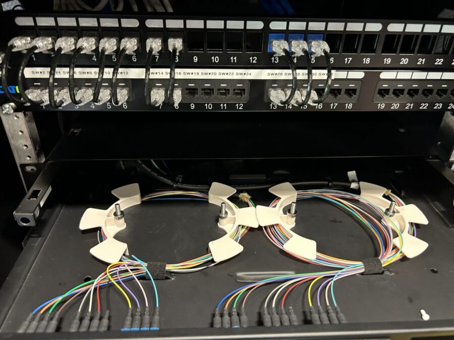 Labeled patch panel with fiber optic pull-out tray showing coiled fiber bundles