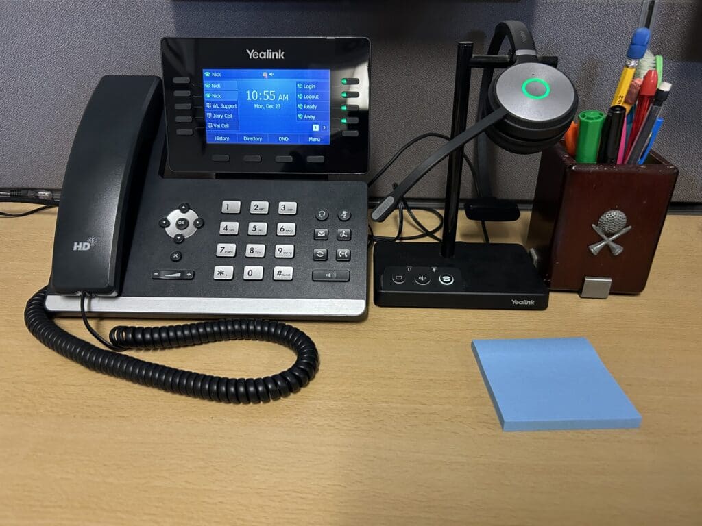 Yealink VoIP desk phone with wireless headset base station on an office desk